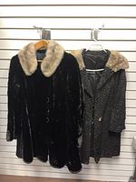 Two coats hanging: glossy faux fur coat and curly pile coat