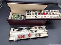 Overall view of maroon three-tier box with trays of assorted Pandora beads and separate narrow tray with necklace cord and beads