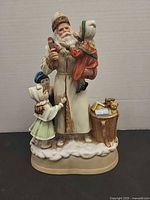 Front view of ceramic Santa music box with children and toy basket