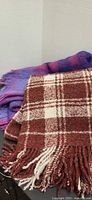 Brown/red plaid throw in front, pink/purple throw behind