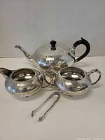 Full four-piece silver-plate tea set displayed