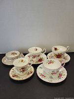 Group of five floral teacups with matching saucers displayed