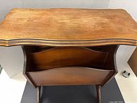 Top view of wooden magazine table showing scalloped edges and surface fading