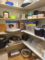 Pantry corner shelves holding Crock-Pot, stock pot, salad spinner, plates, roasting pan, Tupperware and other kitchen items