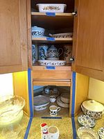 Cabinet showing multiple shelves of Portmeirion pieces, glass bowls and additional serveware