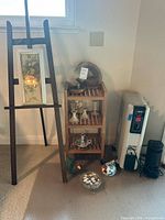 Overview of easel with framed art, wood shelf, heater, air purifier, floor decor