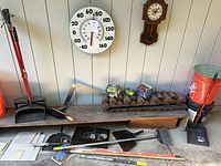 Overall view of thermometer, clock, tools, fire logs, bucket and hand tools