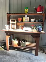 Overall view of wood potting bench with items on shelves and worktop