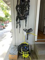 Overview of backpack hanging, pressure washer on floor, car cover in box