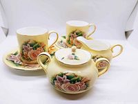 complete demitasse set showing cups, saucers, creamer, sugar bowl with lid, floral pattern and gold trim visible