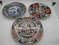 Three Imari style plates laid flat showing patterns