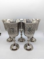 Front view of five matching etched silver-plated goblets