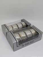Two retail boxes each holding four silver-plated ribbed napkin rings