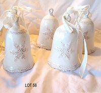 Front view of all four off-white ceramic bells showing snowflake motif and ribbons