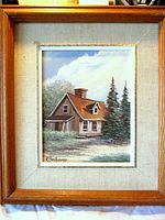 Front view of framed painting showing cabin scene and artist signature