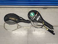 Both tennis rackets with their individual cases