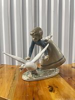 Front view showing girl bending toward goose on textured base