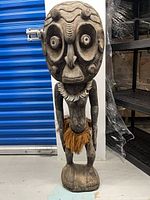 Full view of carved wood tribal statue with necklace and skirt