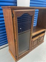 Front angled view showing glass door, TV bay, lower cabinet