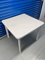 Overall view of white plastic square table with detachable legs installed