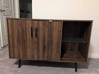 Front view of dark walnut TV stand showing cabinet doors, open shelving, black legs