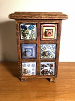 Front view showing six patterned ceramic drawers in wooden cabinet