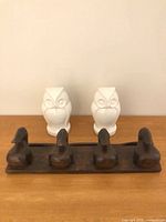 wooden hanger board with five hooks in foreground, two ceramic owls behind