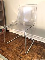 Front angled view of clear acrylic chair showing chrome base