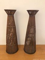 Front view of two bamboo wicker pedestal candleholders
