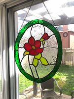Full view of oval stained glass suncatcher hanging in window