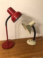 Red and cream gooseneck desk lamps unplugged