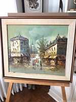 Full view of framed Paris cityscape oil painting on easel