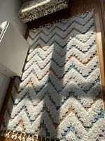 Full view of white shag area rug with multicolor chevron pattern and fringe