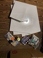 Grouped view showing canvases, paints, brush set on floor