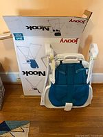 Folded Joovy Nook high chair leaning against original box