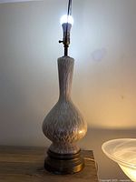 Full view of ceramic lamp, bulb lit, showing base and pattern