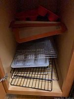 cabinet shelf with silicone mats, muffin pans, wire racks, metal pans