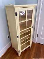 Front view closed showing yellow cabinet with glass door and grid