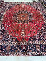 Full view of red Mashhad rug showing entire pattern and borders