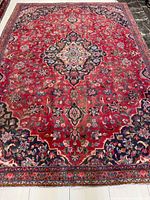 Full view of entire Kashan rug showing red field, borders, and overall condition