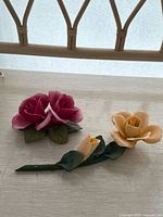 Pink double rose and yellow rose sculptures displayed on surface