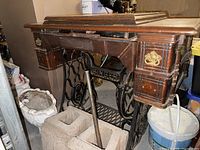 Full view of Singer treadle sewing machine with wood cabinet and cast iron base