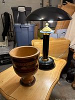 Desk lamp illuminated and wooden pedestal vase on table