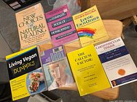 Seven health books laid out on small wooden table