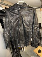 Front view of black leather jacket on hanger