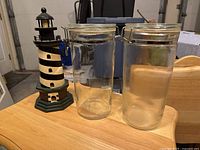 Wood lighthouse model beside two glass jars