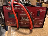 Front view of MotoMaster battery charger showing model, meter and cables