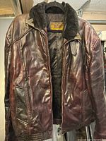 Full front view of brown leather jacket on hanger