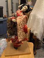 Full view of geisha doll on wooden base