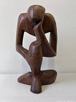 Front view of carved wood abstract thinking man sculpture